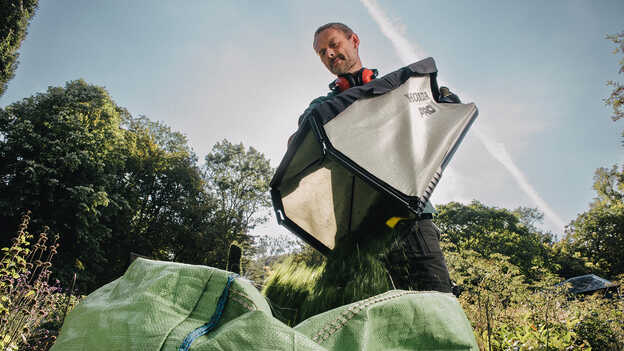 Man emptying a large grass collector.