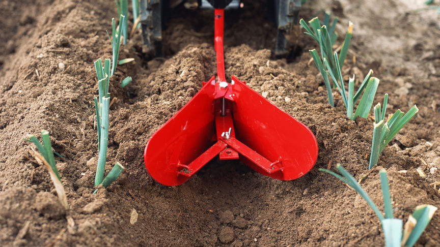 Front view of the counter-rotating tiller working the soil.