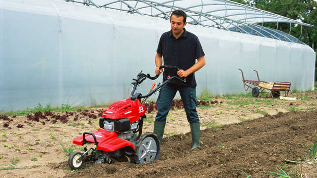 Front view of the counter-rotating tiller working the soil.