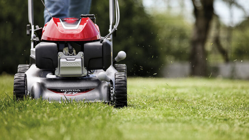 Side view of Honda IZY lawnmower with woman in garden