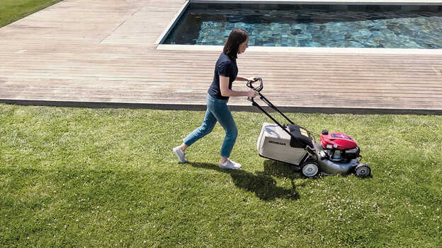 Side view of Honda IZY lawnmower with large capacity grass collector in garden