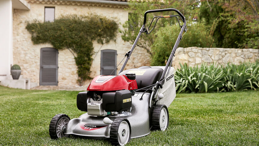 Side view of Honda IZY lawnmower with woman in garden