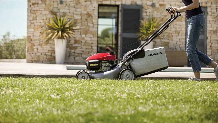 Side view of Honda IZY lawnmower with woman in garden